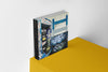 Product photograph of an art cover sketchbook featuring a triptych design of a graffiti-covered payphone, displayed on a vibrant yellow platform against a clean white wall.