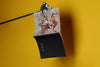Product lifestyle photograph of an art cover sketchbook featuring a stylized textured surreal fish artwork by Nemozine, suspended against a vibrant yellow background.