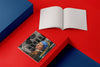 Product photograph of an open, blank sketchbook positioned next to a closed sketchbook featuring the GIRL WITH A PEARL EARRING portrait reinterpretation design by Nemozine, displayed on a contrasting red and blue geometric platform.