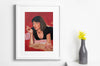 Lifestyle product photograph of the limited edition archival art print PULP FICTN by Goluko, displayed in a white frame next to a grey vase filled with bright yellow flowers.