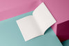 Product photograph of an open, blank sketchbook displayed against a vibrant pink and teal geometric background.