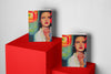 Two portrait-oriented art sketchbooks displayed on red geometric pedestals, featuring a vibrant illustration of a woman with blue eyes, red lipstick, and pearls, holding a cigarette against a neon-colored background.